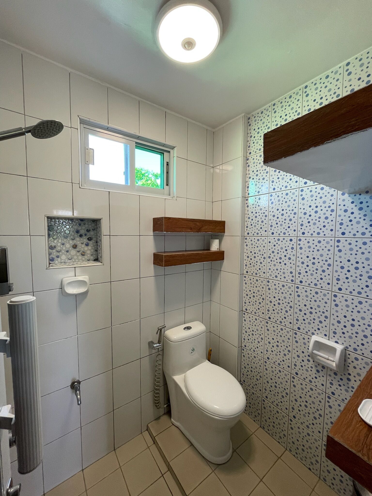 Un baño con inodoro, ducha, ventana y lavamanos.