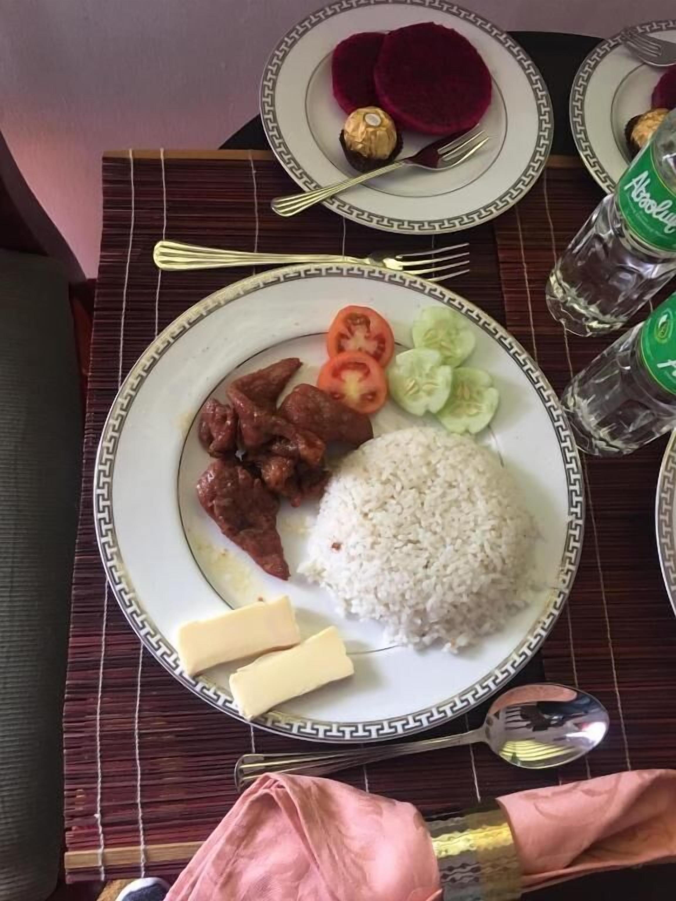 Una mesa de comedor con platos de comida, cubiertos y una botella de agua.