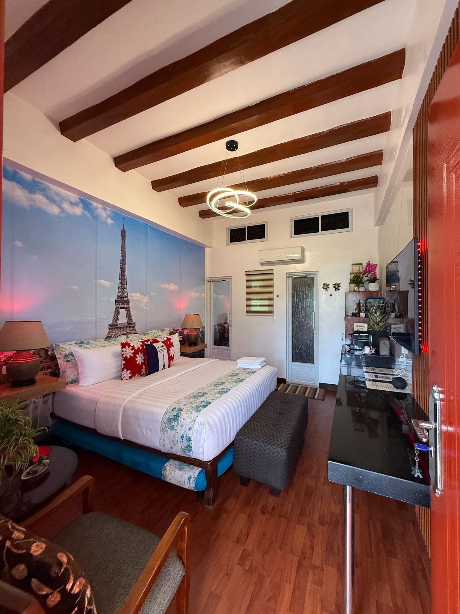 A bedroom with a bed, bedside tables, a desk, and a mirror.