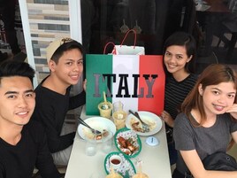 Un grupo de personas sentadas a una mesa con un letrero grande que dice 'ITALY', indicando un ambiente de restaurante.