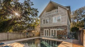 Une maison à deux étages avec une piscine, une terrasse en bois et un jardin clôturé.