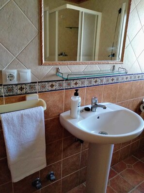 A bathroom with a white sink, a mirror, a towel rack, and a glass shelf. - Alojamiento Rural El Oregano (Campillos)