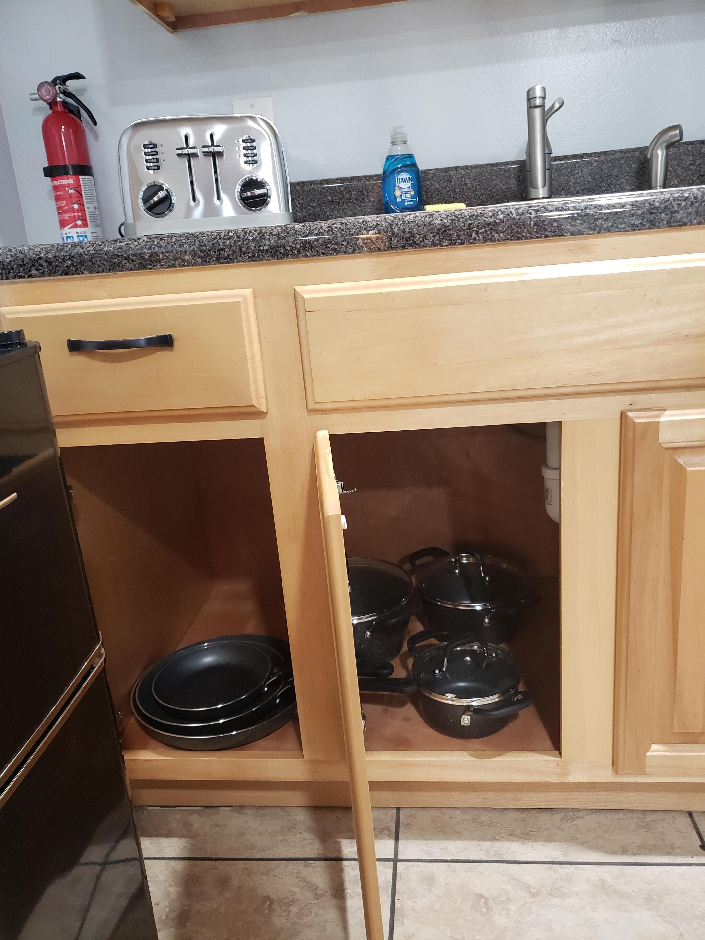 A compact kitchen with a toaster, a sink, and a fire extinguisher.