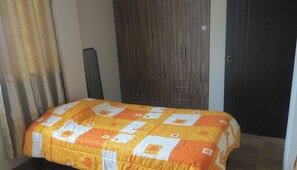 Ein Schlafzimmer mit Bett, Kleiderschrank und Tür.