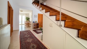 A modern interior with a wooden staircase, a dining area with chairs and a table, and a kitchen visible in the background. - Rooms Raic - double room - No. 1 (Dubrovnik)