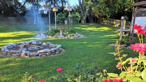 Un jardín bien cuidado con un hogar de piedra, césped verde exuberante y flores rojas vibrantes.