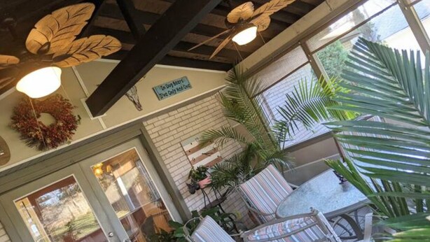 Un patio techado con una mesa y sillas, un cartel que indica que es zona para perros y un muro de ladrillo.