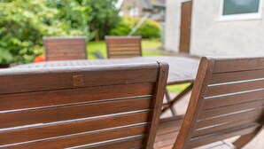 A wooden outdoor seating area with a table and chairs, a brick planter, and a house in the background. - Avondale Bungalow -  A cottage that sleeps 4 guests  in 2 bedrooms (Staveley)