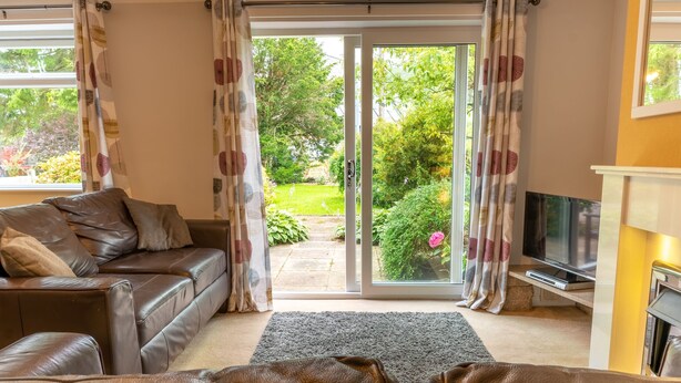A living room with a brown leather sofa, a flat-screen TV, and a fireplace. - Avondale Bungalow -  A cottage that sleeps 4 guests  in 2 bedrooms (Staveley)