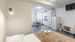 A modern hotel room with a bed, a wooden table, a desk, and a kitchenette. - Apartments Sonja - Studio (Pucisca)