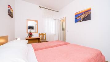 Ein Schlafzimmer mit zwei Betten, einem Schreibtisch, einem Stuhl, einem Spiegel und einem Bild an der Wand.