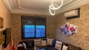A living room with a sectional sofa, a glass coffee table, and a wall-mounted air conditioner. - Very nice apartment F3 comfortable. (Agadir)