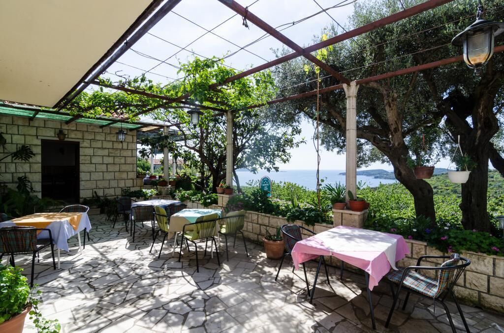 Eine Terrasse im Freien mit Steinböden, Tischen mit Tischdecken und Stühlen.