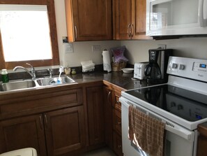 Kitchen area with a sink, stove, microwave, and toaster.