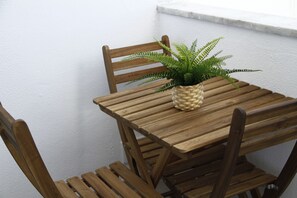 Ein Holztisch mit einem gewebten Blumentopf, begleitet von Holzstühlen.