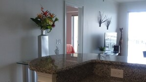 Una cocina con encimeras de granito, un armario blanco y un florero con flores.