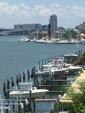 A marina with boats docked along a waterfront, surrounded by buildings and greenery.