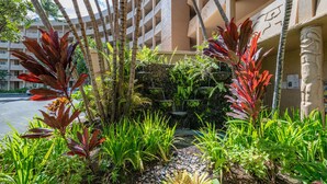 Un patio de hotel con pared de piedra, plantas tropicales y una fuente de agua.