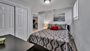 A bedroom with a patterned bedspread, a red pillow, and a painting on the wall. - Beautiful 2 bedroom walkout basement apartment close to U of G (Guelph)
