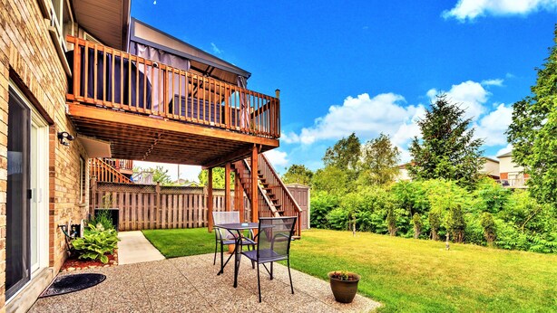A backyard patio with a wooden deck, outdoor furniture, and a potted plant. - Beautiful 2 bedroom walkout basement apartment close to U of G (Guelph)