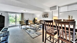 A modern living room with a piano, a sofa, a coffee table, and a dining table with chairs. - Beautiful 2 bedroom walkout basement apartment close to U of G (Guelph)