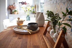 Une table en bois, sur laquelle se trouvent un bol en céramique, une cuillère et un vase avec des plantes.
