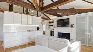 Una cocina moderna con armarios blancos, una chimenea y un televisor encima.