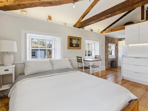 Ein Schlafzimmer mit Bett, Nachttisch, Lampe und Fenster.