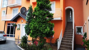 Un edificio de varios pisos con balcones, una escalera y un jardín con diversas plantas y flores.