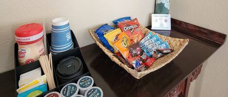 A coffee bar setup with a sign, snacks, and coffee containers.