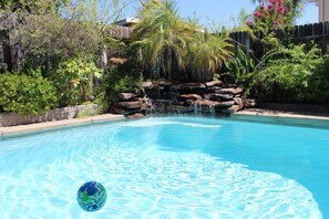 Una piscina azul cristalina con cascada y un globo en el agua.