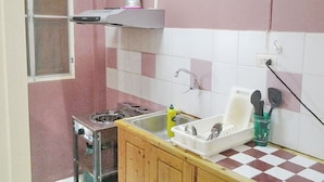 A small kitchen with a gas stove, a sink, and a dish rack.