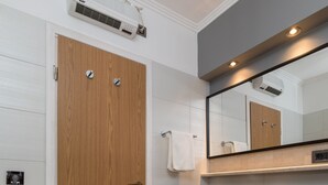 A modern bathroom with a wooden door, a built-in washing machine, a sink, and a mirror above the counter.