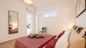 A bedroom with a bed, a chair, a window, and a door.
