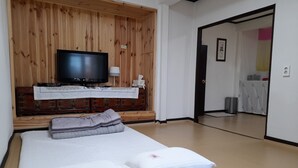 Ett sovrum med en sänggavel i trä, en tv, ett nattduksbord med en lampa och en säng med kuddar och ett täcke.
