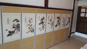 En rad traditionella skjutdörrar prydda med kinesisk kalligrafi och naturmotiv.