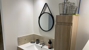 A bathroom with a white sink, a mirror, and a wooden cabinet. - Comfortable studio in the Gulf of St Tropez (Cavalaire-sur-Mer)