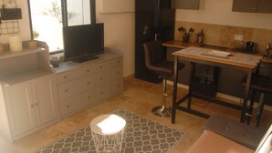 A compact kitchen with a dining area, a TV, and a window providing natural light. - Comfortable studio in the Gulf of St Tropez (Cavalaire-sur-Mer)
