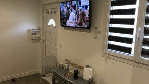 A living room with a TV mounted on the wall, a table with mugs, a kettle, and a chair. - independent house (Chartres)