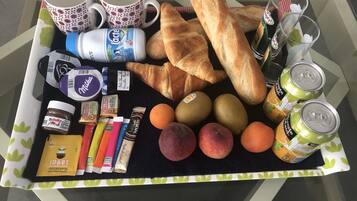 Een dienblad met eten, waaronder croissants, appels, perziken en Nutella.