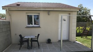 A small, single-story building with a tiled patio, a table with chairs, and a door. - independent house (Chartres)