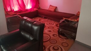 Ein Wohnzimmer mit einem roten Sofa, einem schwarzen Ledersessel und einem gemusterten Teppich.