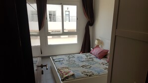 Ein Schlafzimmer mit Bett, Vorhängen, einem Fenster und einer Tür.