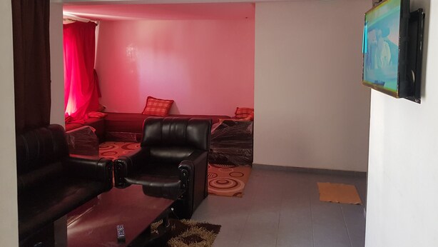 Ein Wohnzimmer mit roter Wand, einer Couch, einem Couchtisch und einem an der Wand montierten Fernseher.