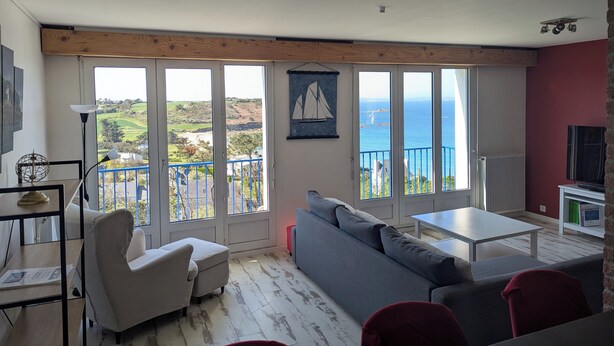 Een woonkamer met een groot raam met uitzicht op een mooi landschap, een bank, een tafel en een televisie.
