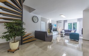 A modern living room with a staircase, a large potted plant, and two sofas. - Charming villa just 3 minutes from the beach (Porec)
