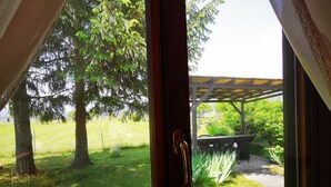 A window with a view of a grassy area, trees, and a pergola. - MERIKOTKA: cozy wooden cottage sLOVEnia with farm view & wonderful neighborhoods (Braslovče)