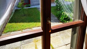 A view through a window of a wooden house with a red door and a small balcony. - MERIKOTKA: cozy wooden cottage sLOVEnia with farm view & wonderful neighborhoods (Braslovče)