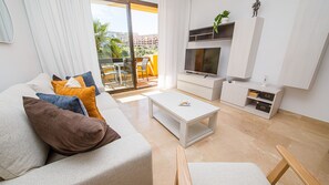 A modern living room with a sofa, coffee table, TV, and storage units.