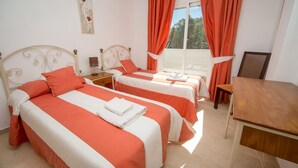 Une chambre d’hôtel avec deux lits, une table en bois et une fenêtre avec des rideaux.